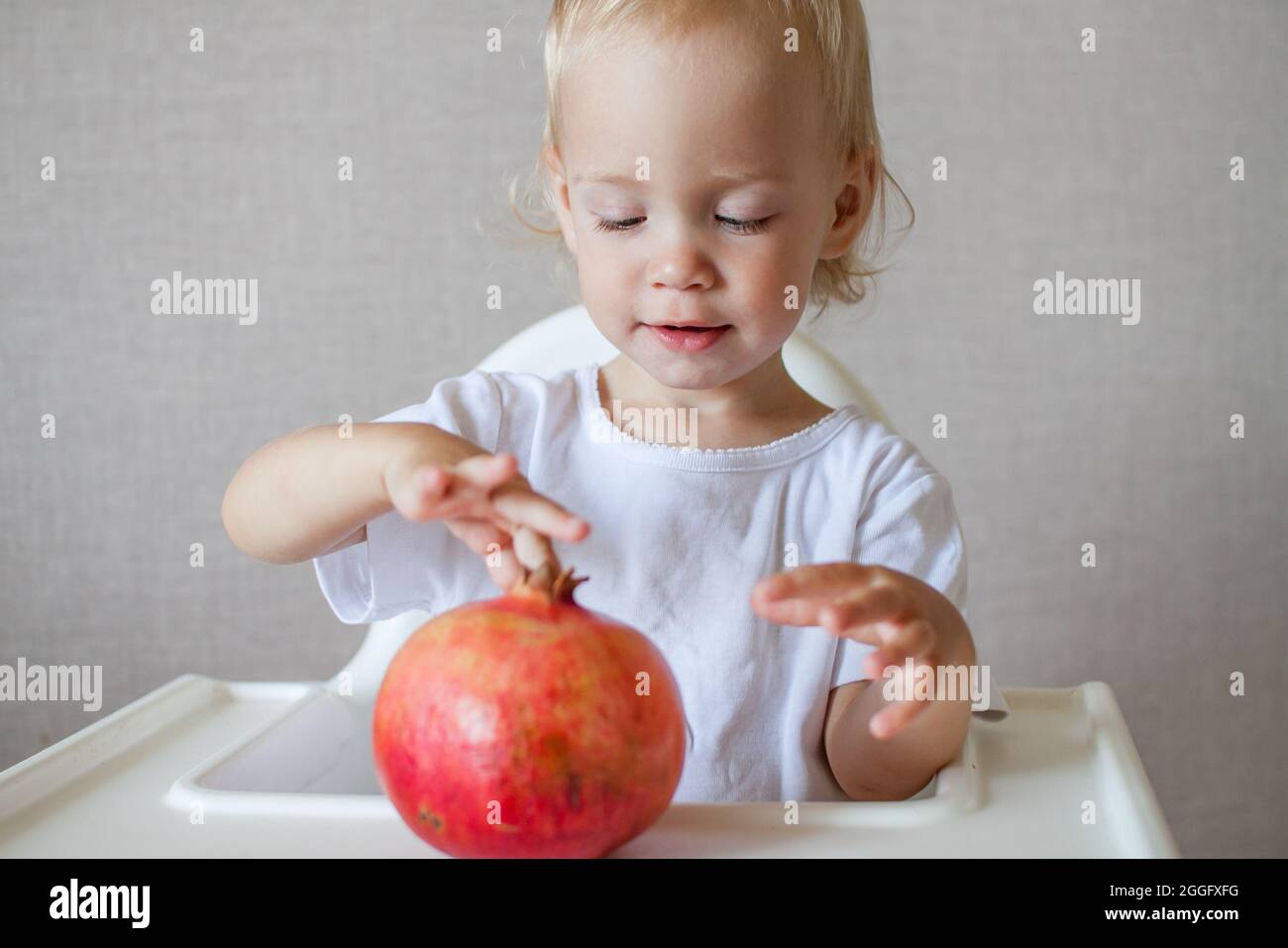 Porträt eines kleinen Mädchens, das einen Granatapfel hält und untersucht. Das Symbol des jüdischen neuen Jahres. Rosh Hashana. Stockfoto