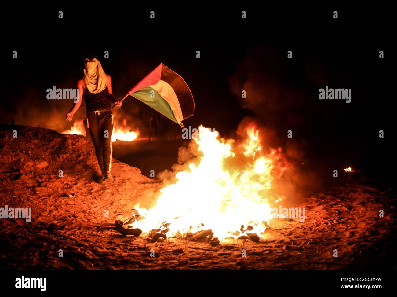 Palästinensische Gebiete, Gazastreifen. August 2021. Während der Zusammenstöße mit der israelischen Armee, die als „nächtliche Verwirrung“ bezeichnet wird, verbrennen palästinensische Demonstranten Gummireifen entlang des Grenzstreifens, der den Gazastreifen und Israel östlich von Khan Junis im südlichen Gazastreifen trennt, und protestieren gegen die andauernde Blockade des Gazastreifens. Gaza. Stockfoto