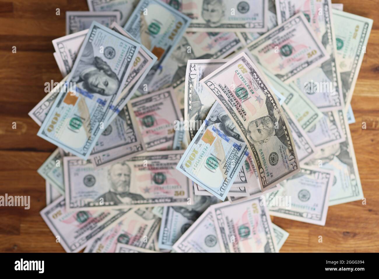 Viele verschiedene Dollarscheine, die auf einem Holztisch liegen, machen den Hintergrund aus der Nähe Stockfoto
