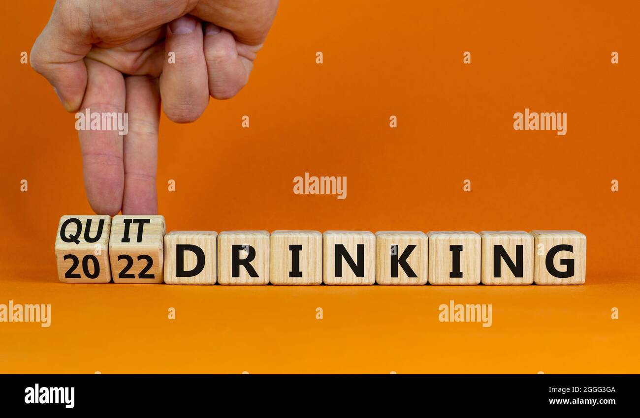 Aufhören zu trinken 2022 neue Jahre Auflösung Symbol. Der Geschäftsmann dreht Holzwürfel mit den Worten „2022 Schluss mit dem Trinken“. Schöner orangefarbener Hintergrund, Kopie-SPAC Stockfoto