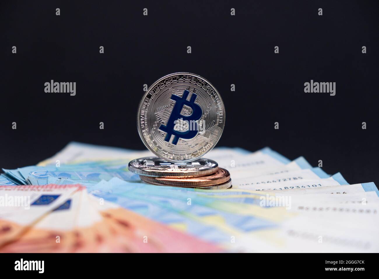 Bitcoins mit blauem Symbol im Fokus liegt auf 20 und 10 Euro Banknoten. Bitcoins auf zehn- und zwanzig-Euro-Banknoten auf dunklem Hintergrund. Stockfoto