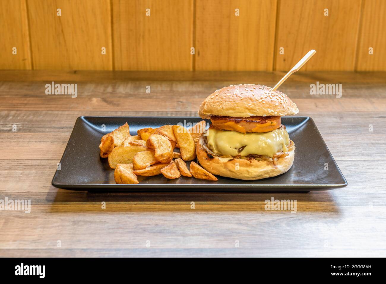 Rinderburger mit geschmolzenem Käse mit Foie Gras und gebratenem Speck, pommes Frites und Brot mit Sesam Stockfoto