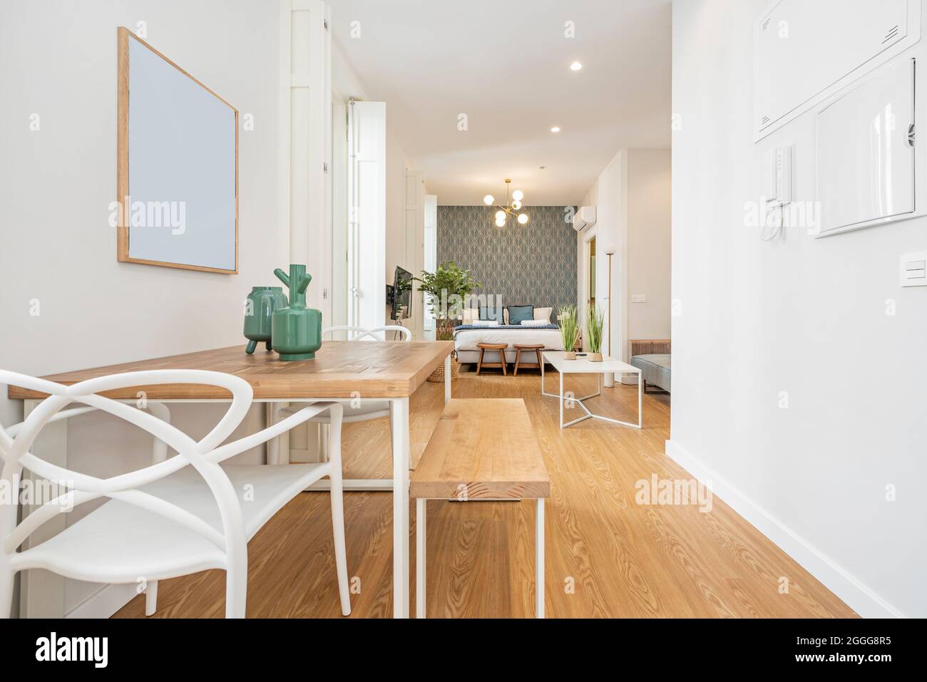 Studio-Apartment mit minimalistischem Dekor mit Esstisch im Vordergrund und Schlafzimmer im Hintergrund in einer Ferienwohnung Stockfoto