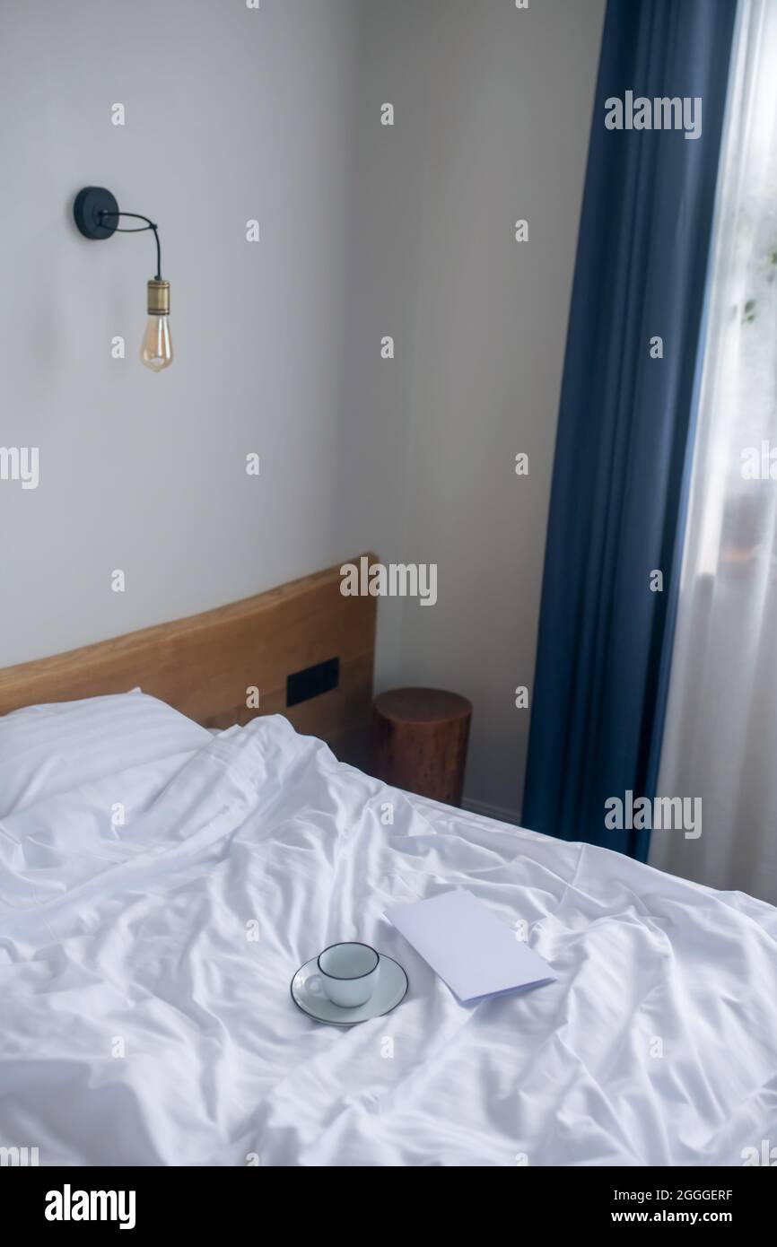 Bett mit weißer Bettwäsche am Morgen Stockfoto