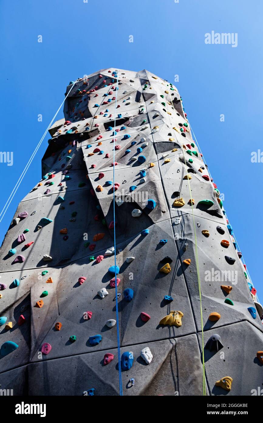 Hohe Kletterwand mit Seilen und verschiedenen Leisten Stockfoto