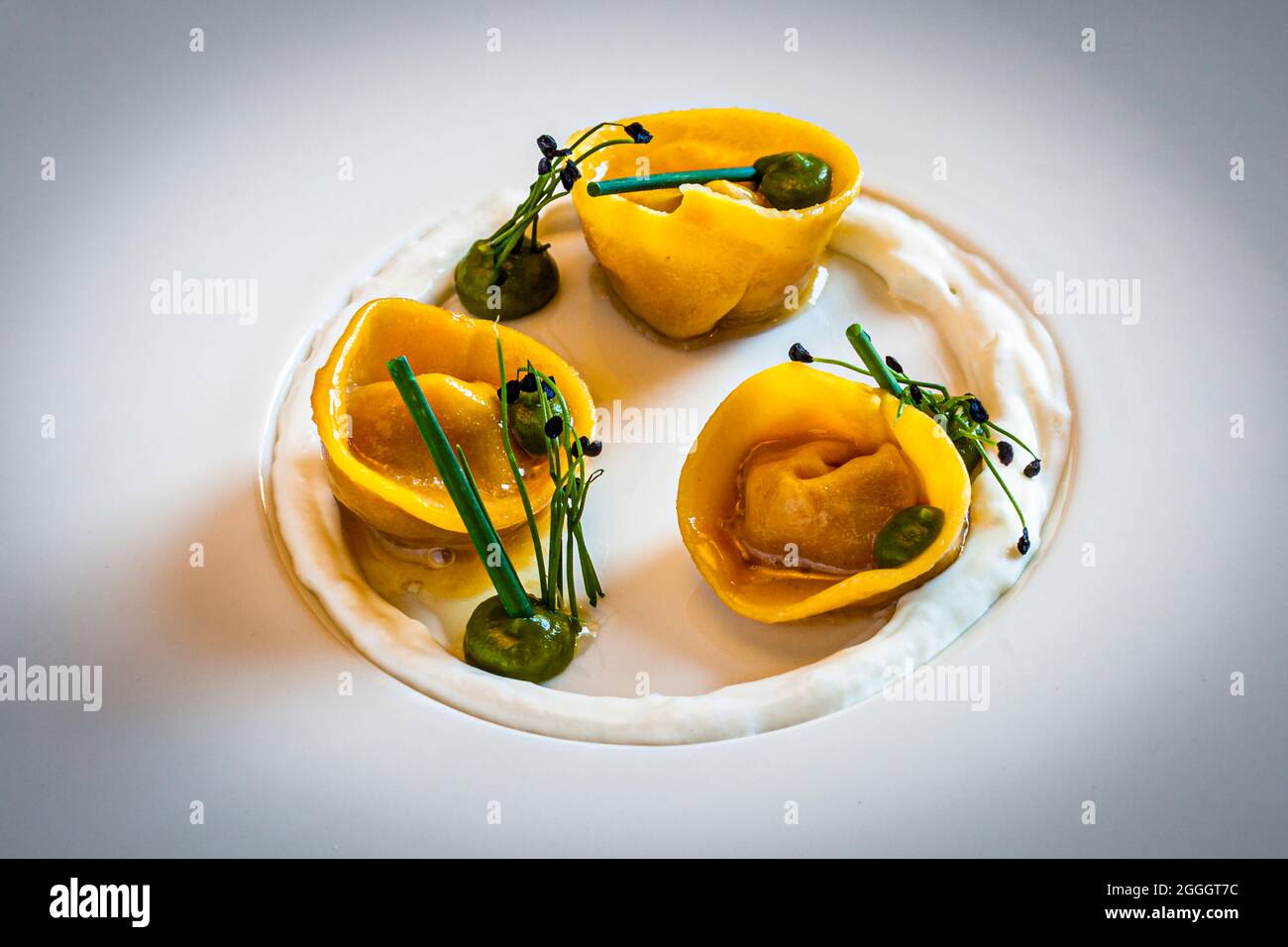 Vorspeise von Küchenchef Hannes Stuffer. Tortellini mit Schnittlauch-Creme und halbflüssiger Tomatenfüllung im Hotel Hohenwart in Schenna, Italien Stockfoto