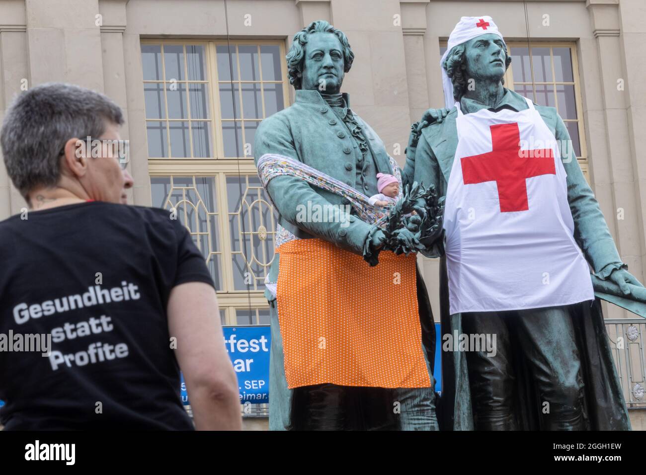 Weimar, Deutschland. September 2021. Ellen Ost, eine Krankenschwester, steht vor den überdachten Statuen von Goethe und Schiller. Die Einhüllungsaktion der Partei die Linke am Goethe- und Schiller-Denkmal soll auf die Pflegekrise aufmerksam machen. Quelle: Michael Reichel/dpa/Alamy Live News Stockfoto