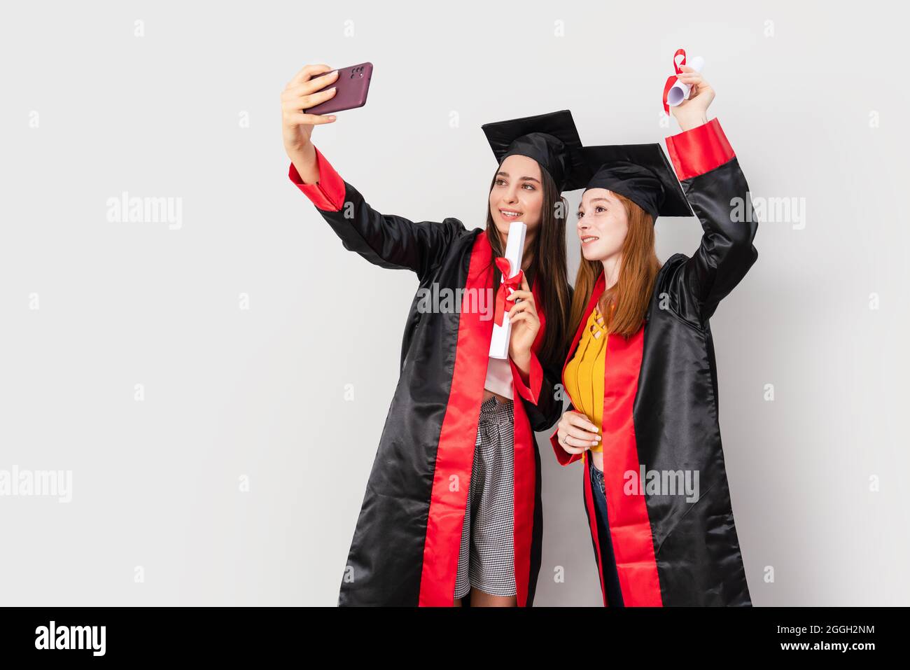 Zwei hübsche Studentinnen, die ihren Abschluss feiern und Selfie machen. Hochwertige Fotos Stockfoto
