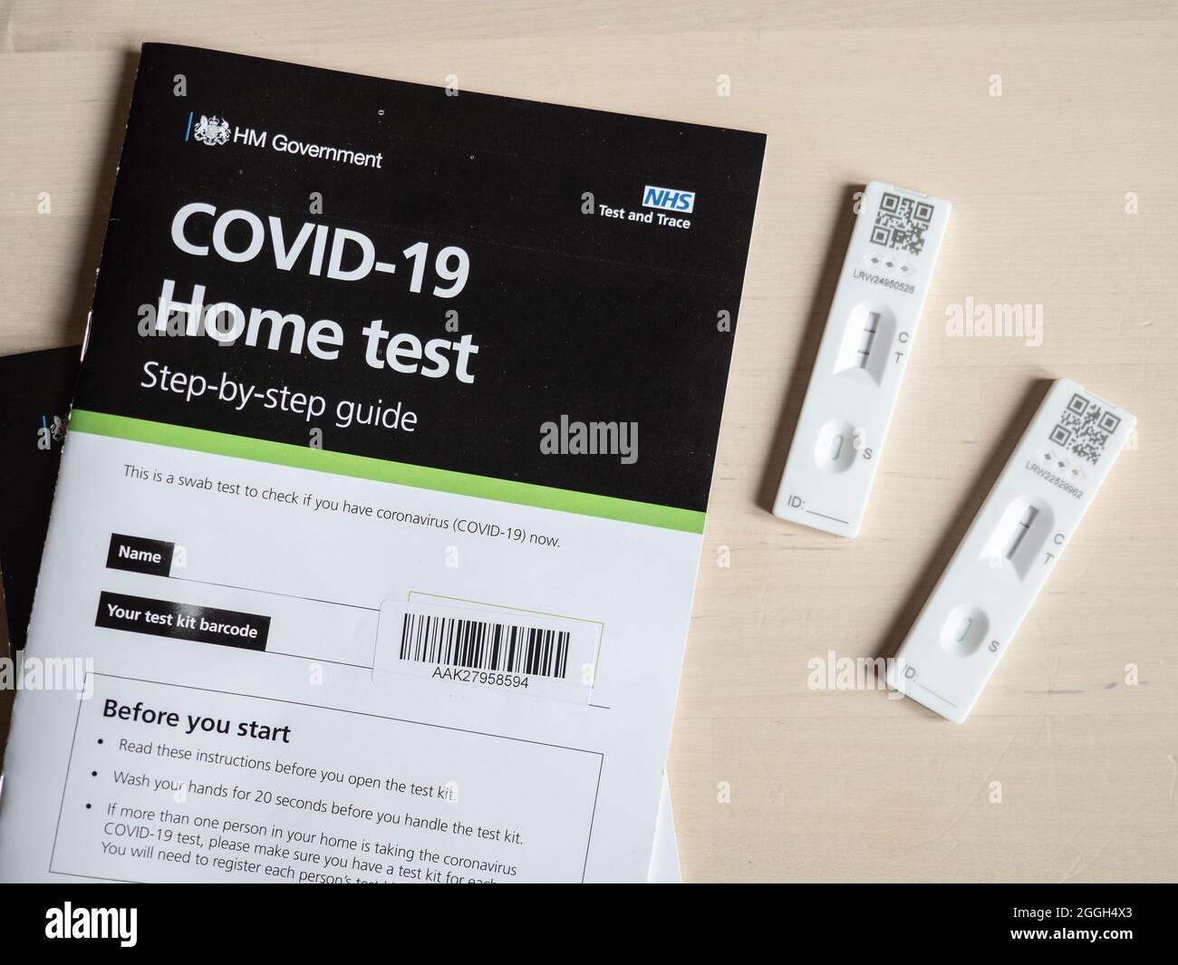 Positives COVID-19-Testergebnis. Sowohl positive als auch negative Testergebnisse eines UK NHS lateral flow Corona Virus Home Testkits mit Benutzerhandbuch. Stockfoto