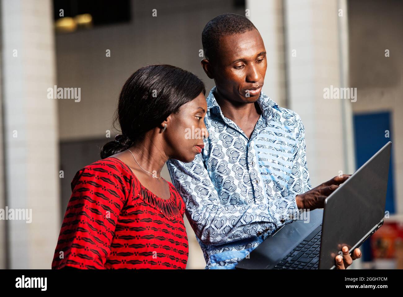 Junger afrikanischer Geschäftsmann zeigt den Projektplan mit dem Finger auf dem Laptop-Bildschirm, während eine Frau lächelt Stockfoto