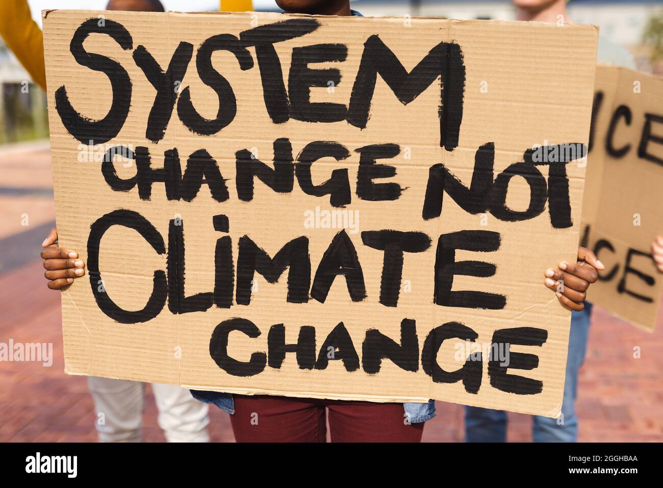 afroamerikanische Frau mit Plakat, auf dem der Systemwechsel und nicht der Klimawandel beim protestmarsch zu sehen waren Stockfoto