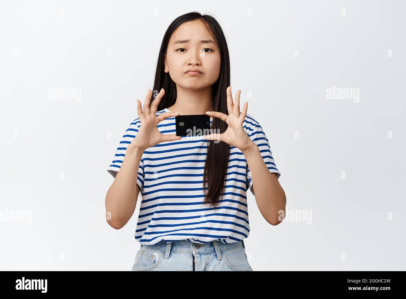 Bild der asiatischen Brünette Mädchen runzelte und Pouts enttäuscht, zeigt schlechte Kreditkarte, kein Geld, stehen über weißem Hintergrund Stockfoto