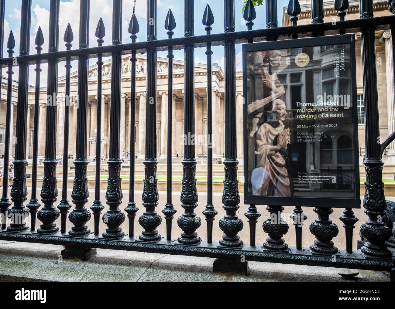 Das British Museum, London. Ein Blick auf das kulturelle Wahrzeichen durch seine Eisengeländer mit einem Plakat, das eine Ausstellung über Thomas Becket fördert. Stockfoto