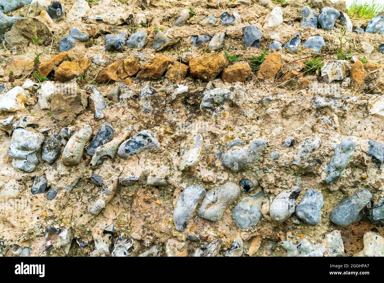 Aus nächster Nähe, römische Mauer, die im 3. Jahrhundert als Teil einer Festung erbaut wurde. Reihen von Feuersteinen, die in einem gerichteten Stil mit einer Reihe von gelbbraunen Steinen gelegt wurden. Rekulver. Stockfoto