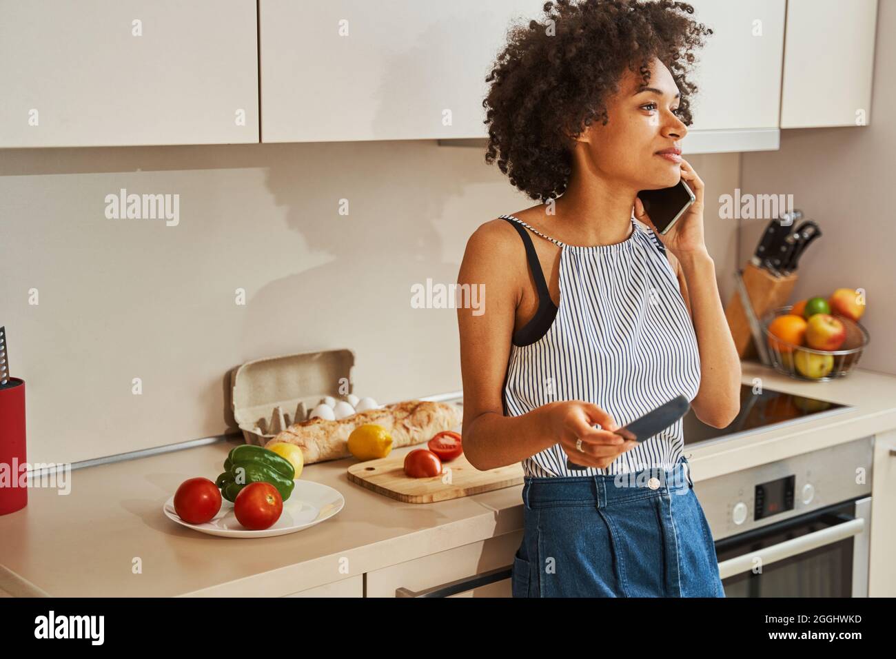 Nette weibliche Köchin mit einem Telefongespräch in der Küche Stockfoto