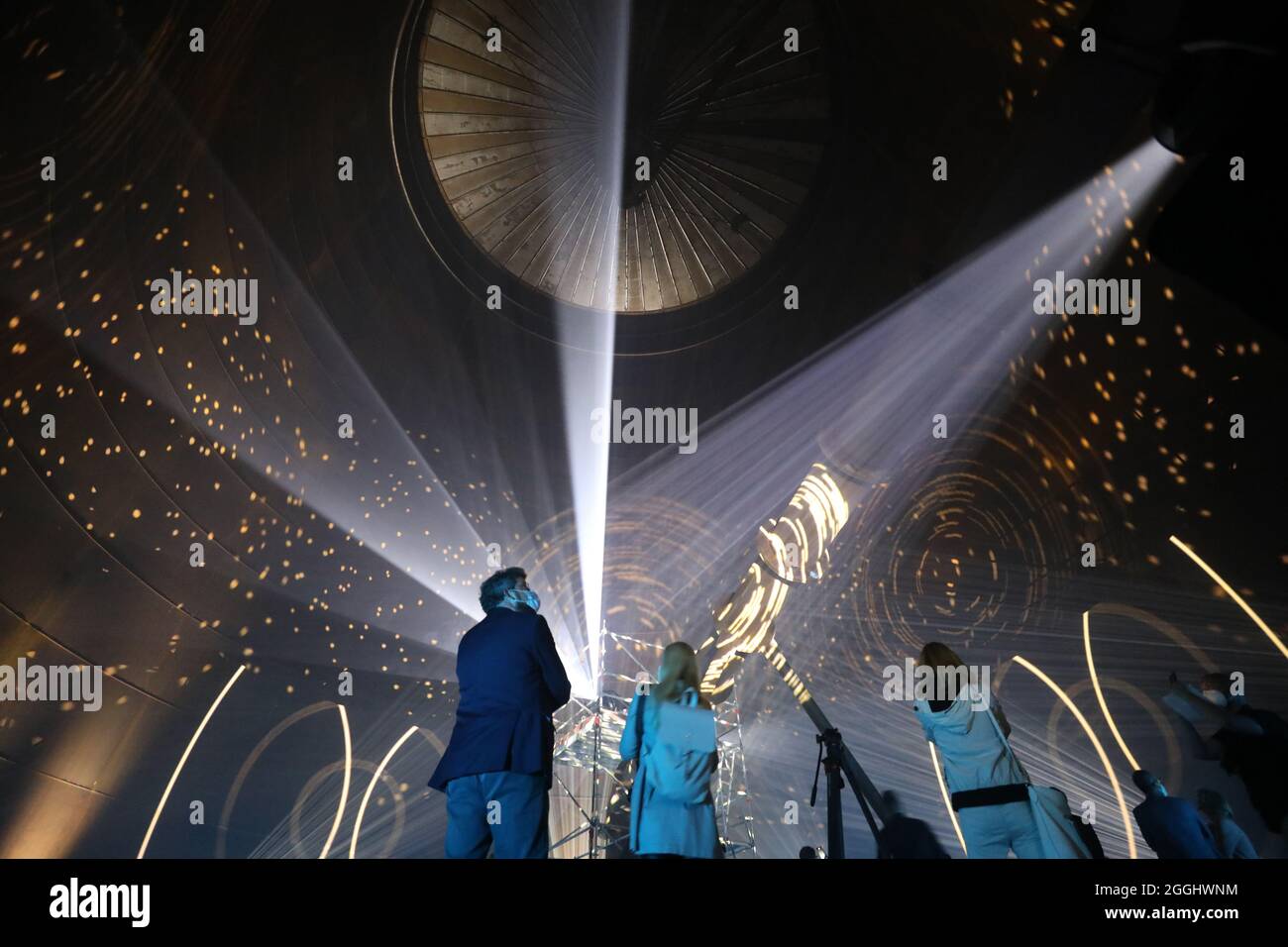 01. September 2021, Mecklenburg-Vorpommern, Rostock: Das Richtfest des neuen Wärmespeichers der Stadtwerke Rostock wird mit einer Laser- und Lichtshow im Inneren gefeiert. Der Grundstein für das 55 Meter hohe Bauwerk am Warnow River wurde vor eineinhalb Jahren gelegt, die Inbetriebnahme ist für das Frühjahr 2022 geplant. Der drucklose Stahltank speichert 45 Millionen Liter Wasser bei einer Temperatur von 98 Grad Celsius und führt es bei Bedarf in das Heiznetz ein. Der Speicher soll unter anderem dazu beitragen, Energie aus Windenergie und Solar pla zu speichern Stockfoto