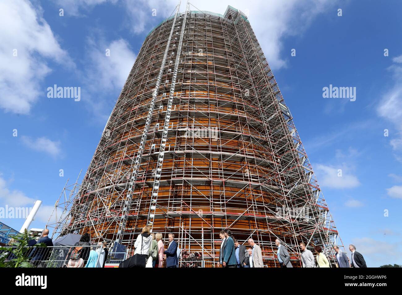 01. September 2021, Mecklenburg-Vorpommern, Rostock: Das Richtfest für den neuen Wärmespeicher der Stadtwerke Rostock wird gefeiert, die Gäste der Veranstaltung sind auf dem Weg in den Speicher. Der Grundstein für das 55 Meter hohe Bauwerk am Warnow River wurde vor eineinhalb Jahren gelegt, die Inbetriebnahme ist für das Frühjahr 2022 geplant. Der drucklose Stahltank speichert 45 Millionen Liter Wasser bei einer Temperatur von 98 Grad Celsius und führt es bei Bedarf in das Heiznetz ein. Das Lager soll unter anderem Lagereinrichtungen unterstützen Stockfoto