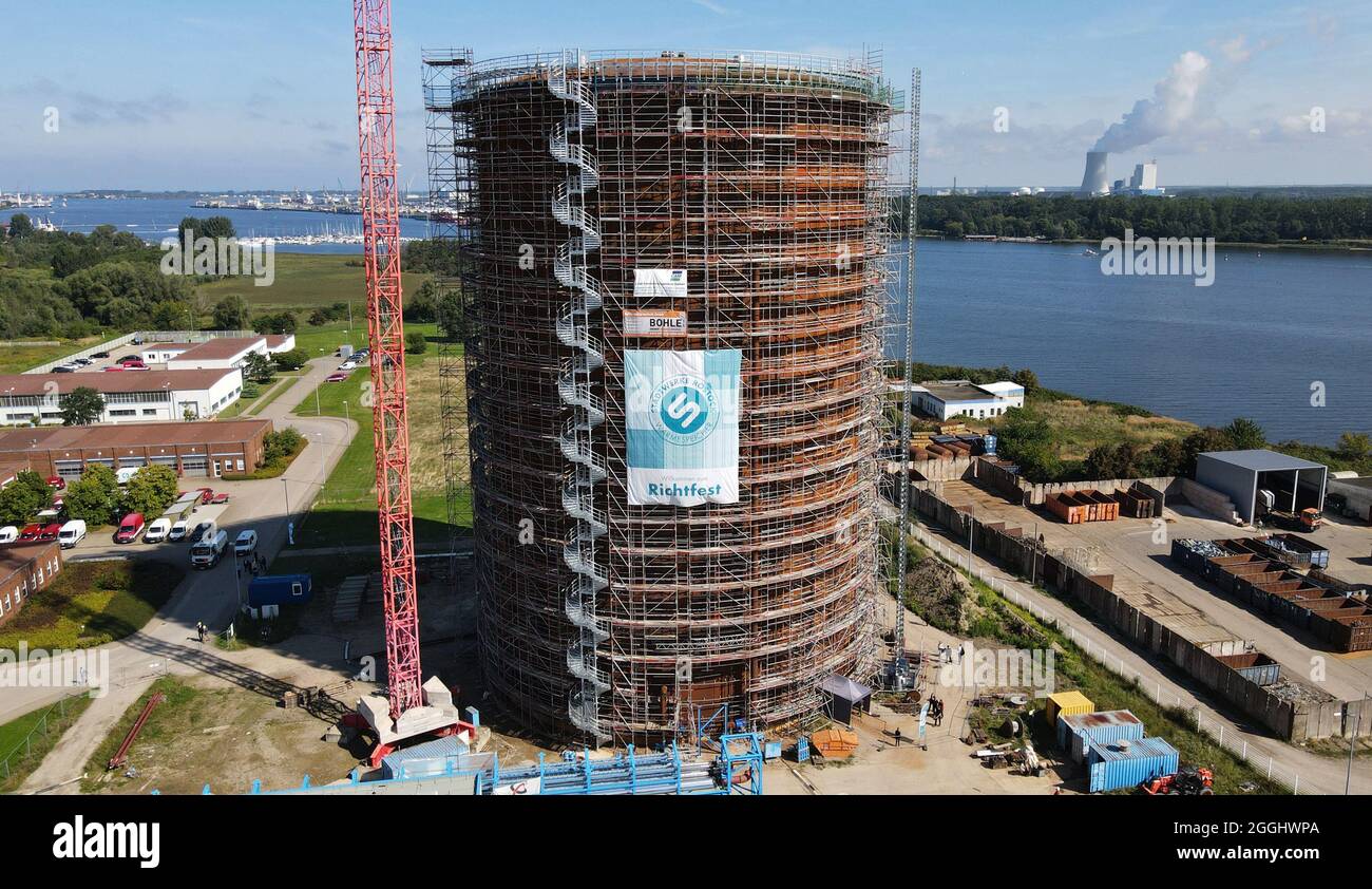 Rostock, Deutschland. September 2021. Das Richtfest für den neuen Wärmespeicher der Stadtwerke Rostock findet statt. Der Grundstein für das 55 Meter hohe Bauwerk am Warnow River wurde vor eineinhalb Jahren gelegt, die Inbetriebnahme ist für das Frühjahr 2022 geplant. Der drucklose Stahltank speichert 45 Millionen Liter Wasser bei einer Temperatur von 98 Grad Celsius und führt es bei Bedarf in das Heiznetz ein. Das Reservoir wird unter anderem helfen, Energie aus Wind- und Solarkraftwerken zu speichern. (Luftaufnahme mit Drohne/Kopter) Quelle: Bern/dpa/Alamy Live News Stockfoto