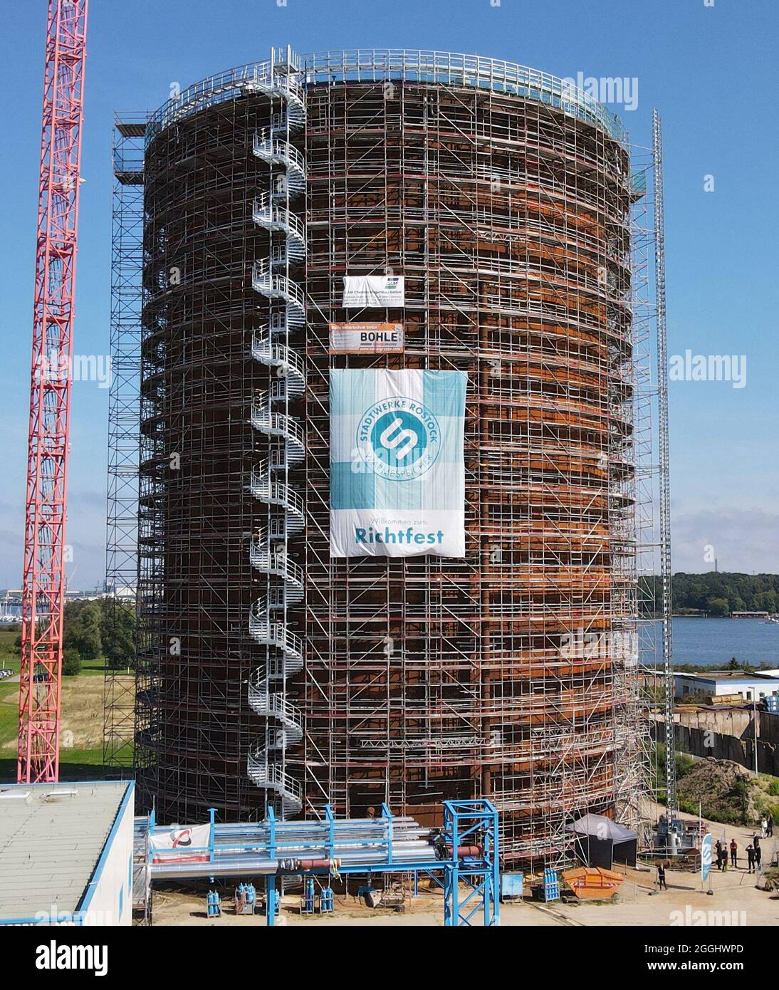 Rostock, Deutschland. September 2021. Das Richtfest für den neuen Wärmespeicher der Stadtwerke Rostock findet statt. Der Grundstein für das 55 Meter hohe Bauwerk am Warnow River wurde vor eineinhalb Jahren gelegt, die Inbetriebnahme ist für das Frühjahr 2022 geplant. Der drucklose Stahltank speichert 45 Millionen Liter Wasser bei einer Temperatur von 98 Grad Celsius und führt es bei Bedarf in das Heiznetz ein. Das Reservoir wird unter anderem helfen, Energie aus Wind- und Solarkraftwerken zu speichern. (Luftaufnahme mit Drohne/Kopter) Quelle: Bern/dpa/Alamy Live News Stockfoto