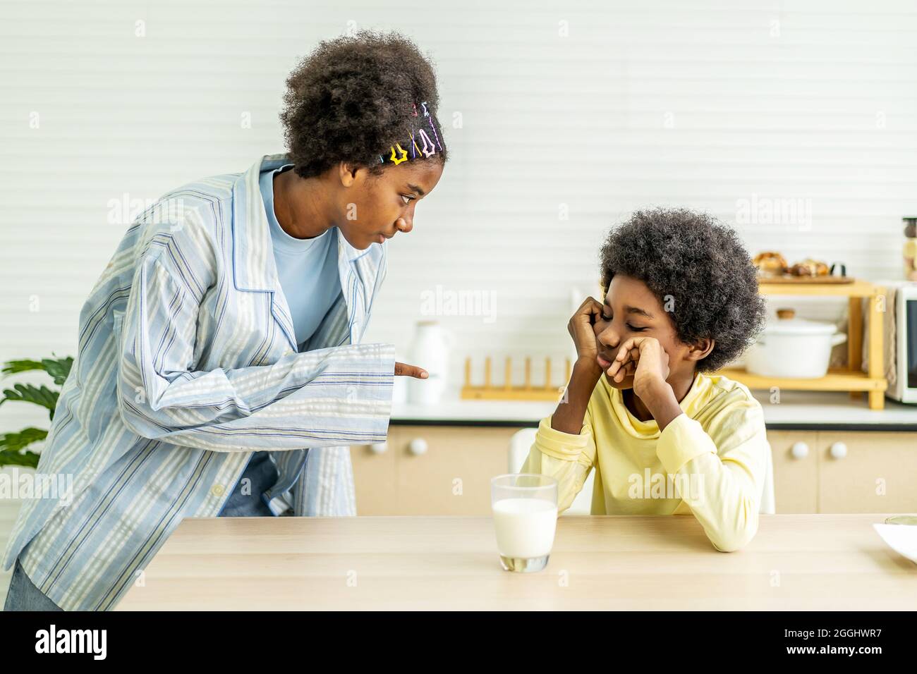 Bruder ist gelangweilt, möchte keine Milch trinken, bis meine Schwester es gezwungen hat Stockfoto