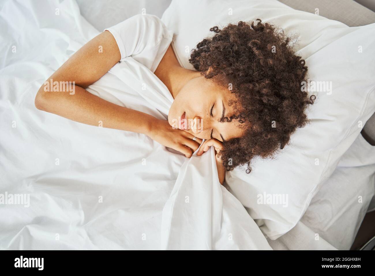 Schöne ruhige Frau mit lockigen Haaren dösen auf dem Kissen Stockfoto