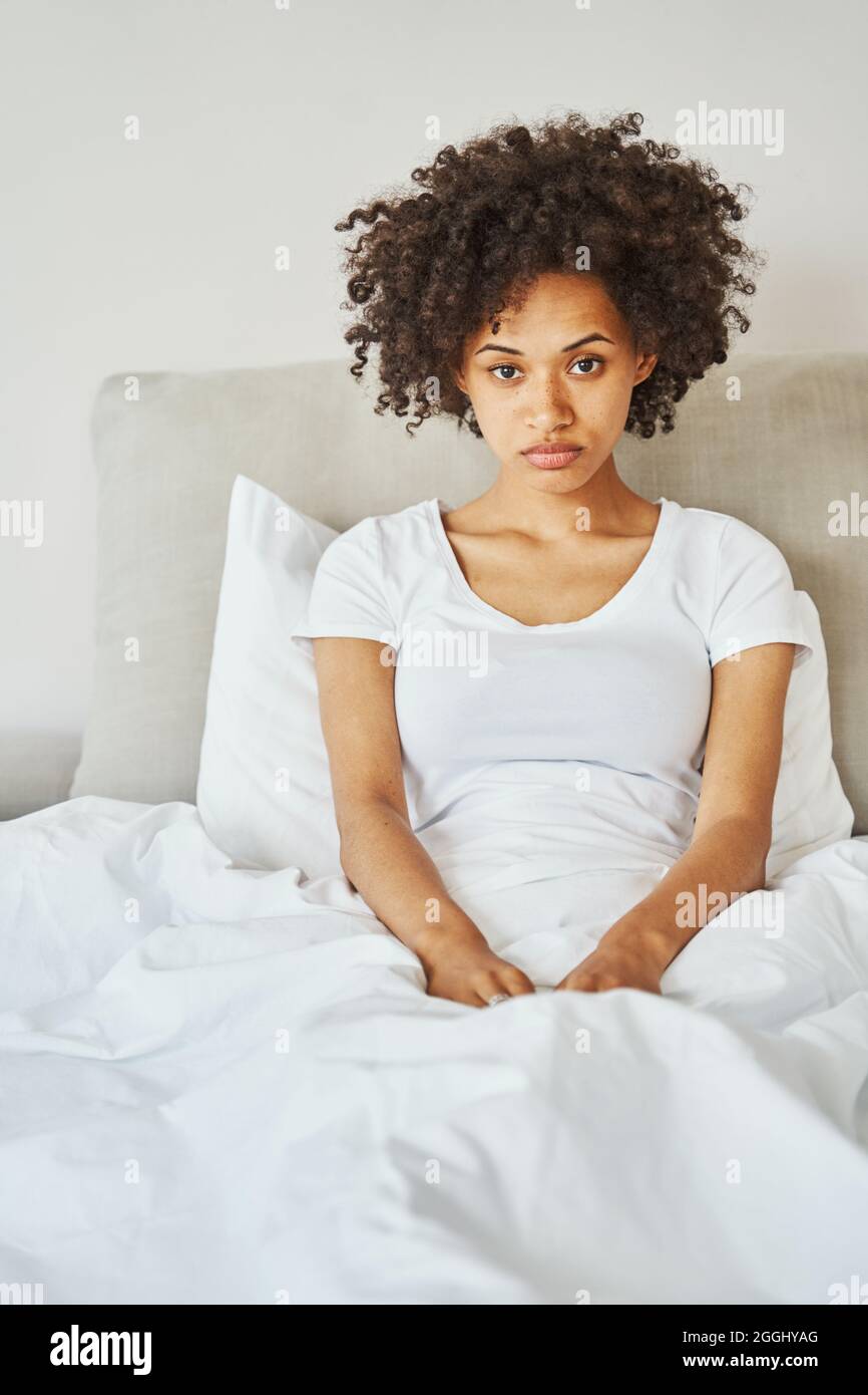 Temperamentvolle, fröhlose Frau saß nach dem Aufwachen in ihrem Schlafzimmer Stockfoto
