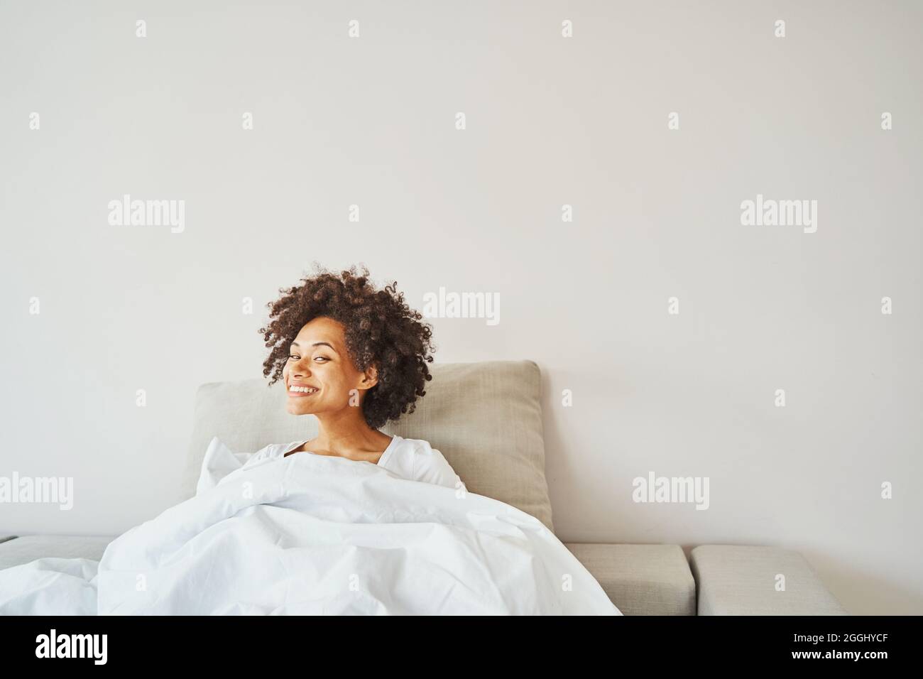 Fröhliche afroamerikanische Dame, die im Bett liegt Stockfoto