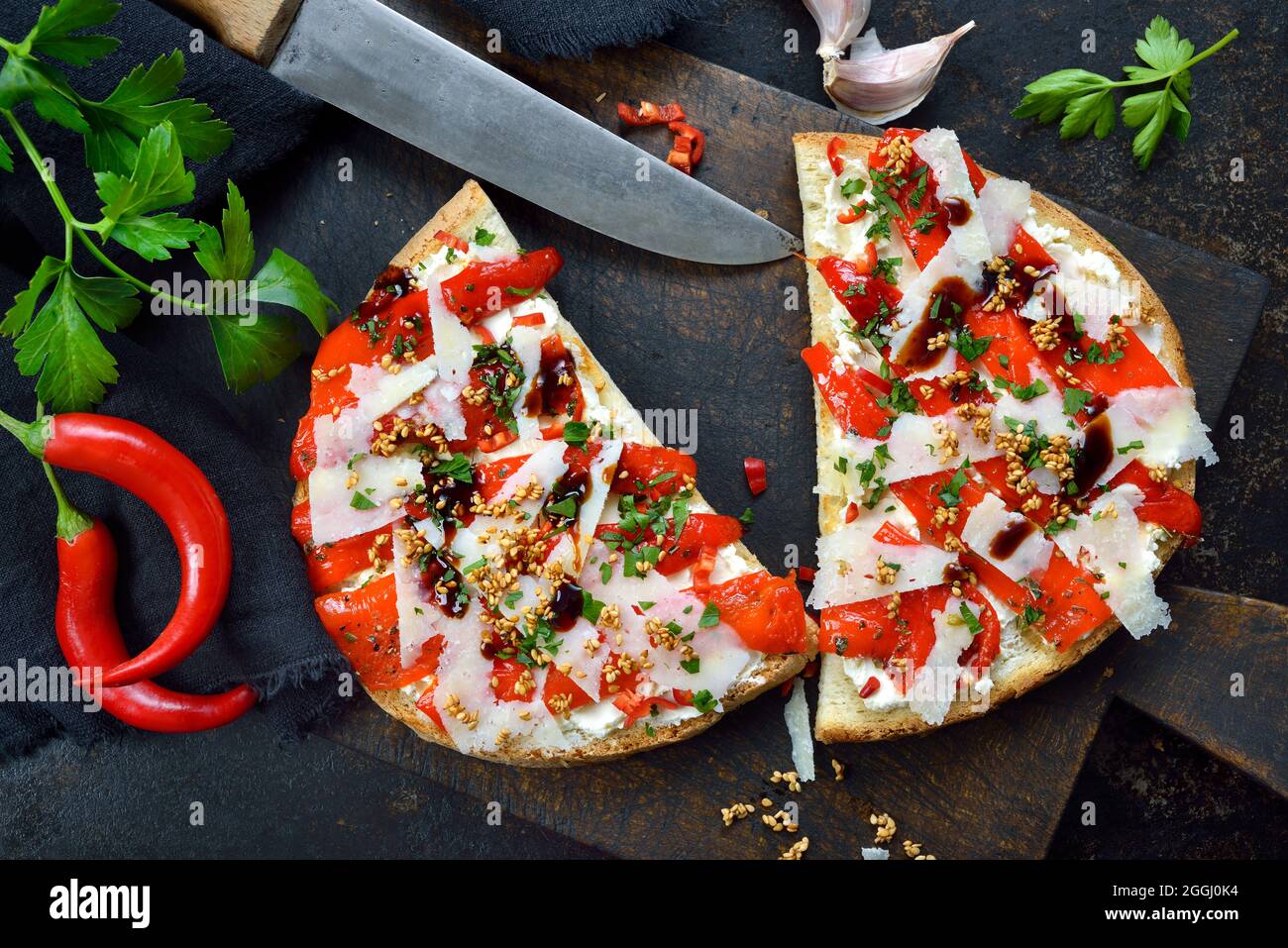 Italienische große Bruschetta mit gegrilltem Spitzpaprika, Chili, Pecorino, Sesam und Frischkäse auf dunklem Hintergrund Stockfoto