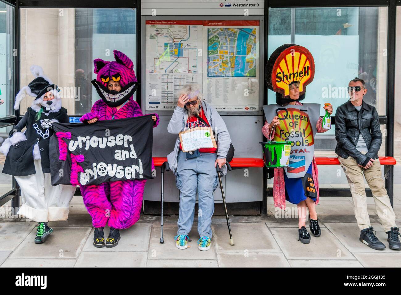 London, Großbritannien. September 2021. The Mad Hatter bringt die Chesthire Cat und die Queen of Fossil Fools (ne Hearts) und sind „Furiouser und Furiouser“ und ruhen sich in einer Bushaltestelle gegenüber dem Ministerium für Energie und Industriestrategie aus - Extinction Rebellion setzt seine zwei Wochen fort, mit einem Greenwash-Protest, der auf dem Parliament Square beginnt, Unter dem Namen Impossible Rebellion. Kredit: Guy Bell/Alamy Live Nachrichten Stockfoto