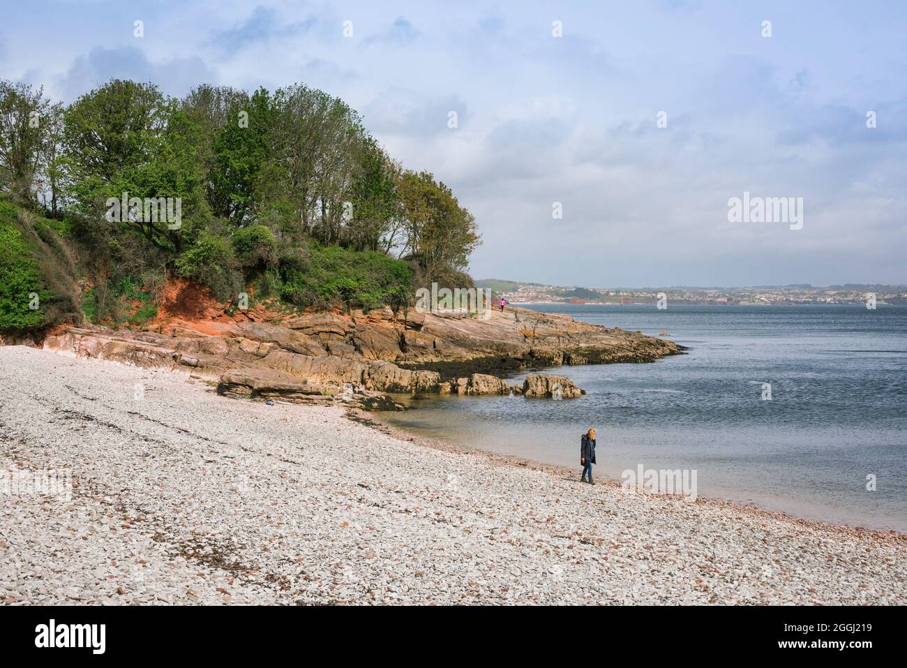 Frauenstrand, Blick auf eine Frau, die allein in einer nachdenklichen Pose steht, während sie Elberry Cove in South Devon, England, Großbritannien besucht Stockfoto