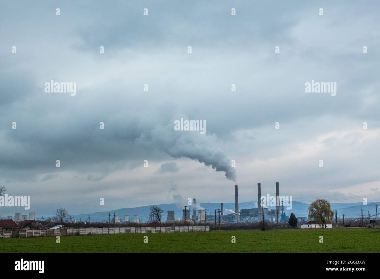 Massiver Industriekomplex, der an einem bewölkten, geschäftigen Tag dampft. Das Ergebnis ist ein weißer dichter Rauch, der das gesamte dicht besiedelte Gebiet bedeckt. Stockfoto