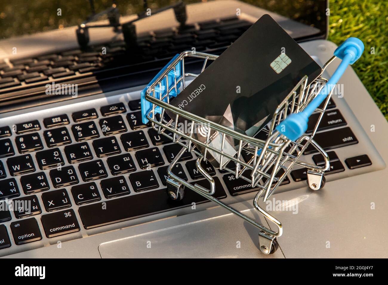 Eine Kreditkarte in einem Mini-Supermarkt-Trolley auf einer Laptop-Tastatur. E-Commerce und Online-Shopping-Konzept. Ideen über zu Hause einkaufen oder Dinge kaufen i Stockfoto