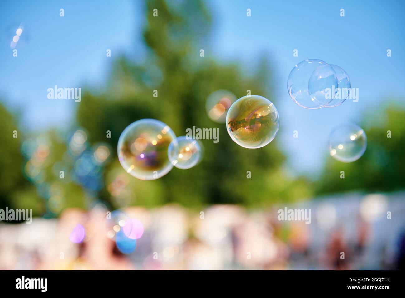Schöne Seifenblasen im Park an einem sonnigen Tag. Eine Menge Blasen in der Luft. Unscharfer Hintergrund. Kindheitskonzept Foto. Großes Bild. Stockfoto
