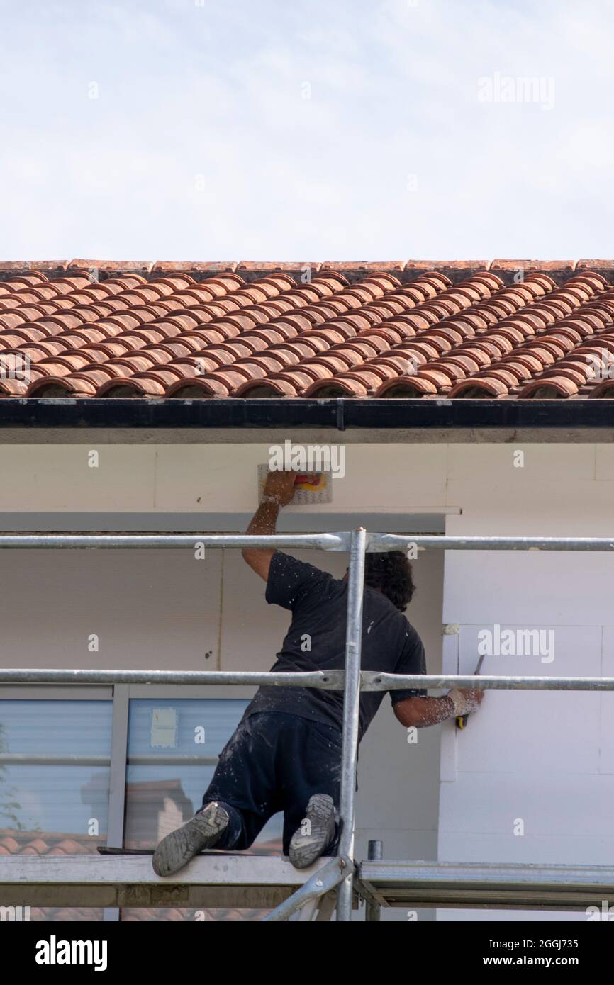 Arbeiter im Bereich Gebäudeeffizienz, der die Fassaden mit Styropor bedeckt, um die Wetterleistung und die akustische Leistung zu erhöhen. Ökologische Nachhaltigkeit Stockfoto
