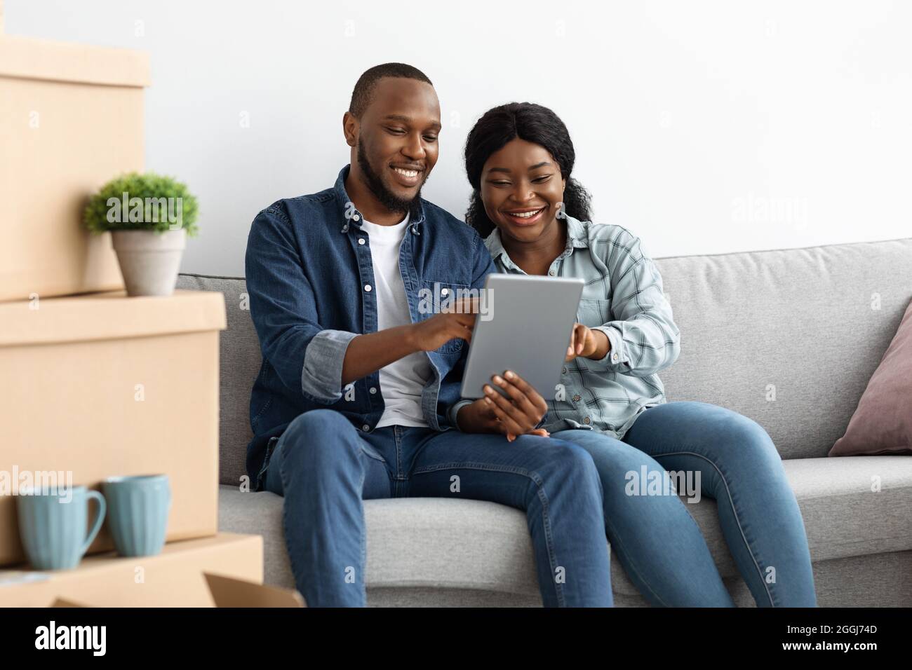 Schwarzes Paar Online-Bestellung Mit Digitalem Tablet Nach Dem Umzug In Neue Wohnung Stockfoto