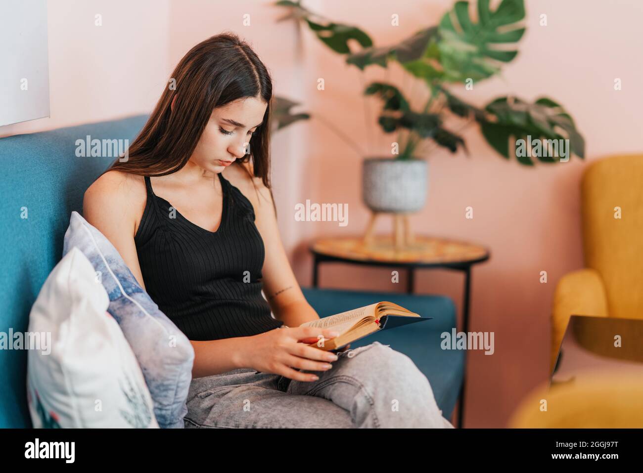 Junge schöne Frau sitzt und liest zu Hause ein Buch. Hochwertige Fotos Stockfoto