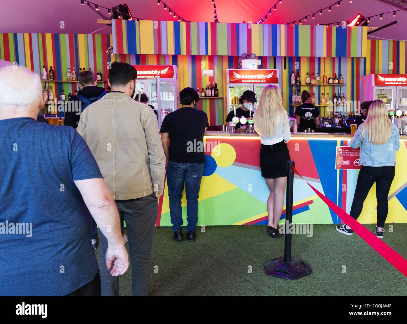 Menschen, die sich an einer Bar anstellen, um Getränke zu kaufen und die soziale Distanzierung während der COVID 19-Pandemie, der Edinburgh Fringe, Schottland, Großbritannien 2021, zu beobachten Stockfoto