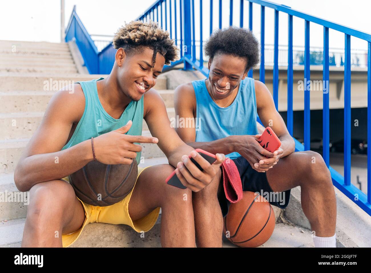 Coole afroamerikanische Männer, die Spaß auf der Straße haben und ihr Telefon benutzen. Stockfoto