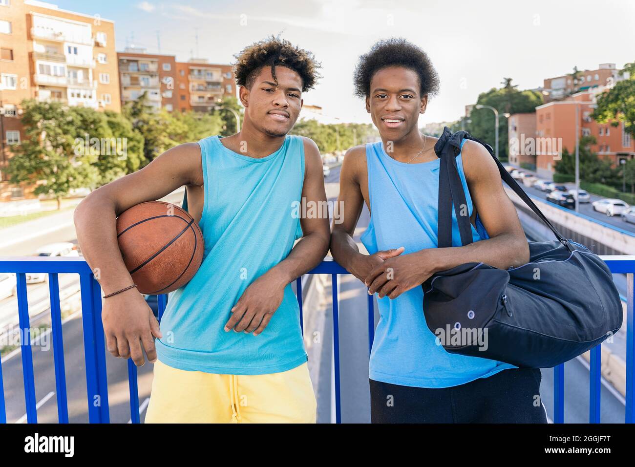 Coole afroamerikanische Männer halten den Basketballball lächelnd und blicken in die Kamera. Stockfoto