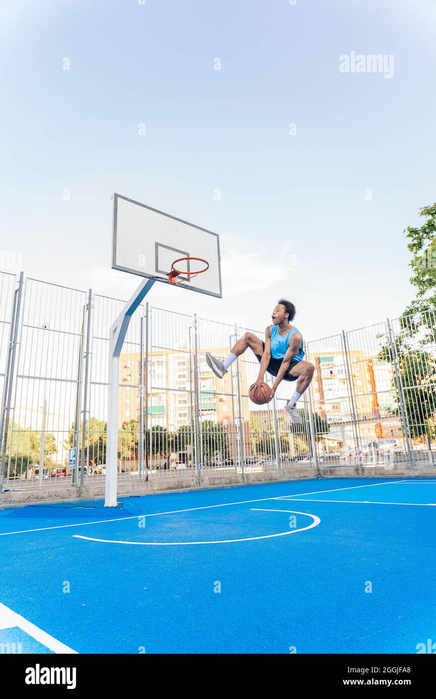 Unbekannter afrikanischer Junge in Sportkleidung Basketball spielen und den Ball werfen. Stockfoto