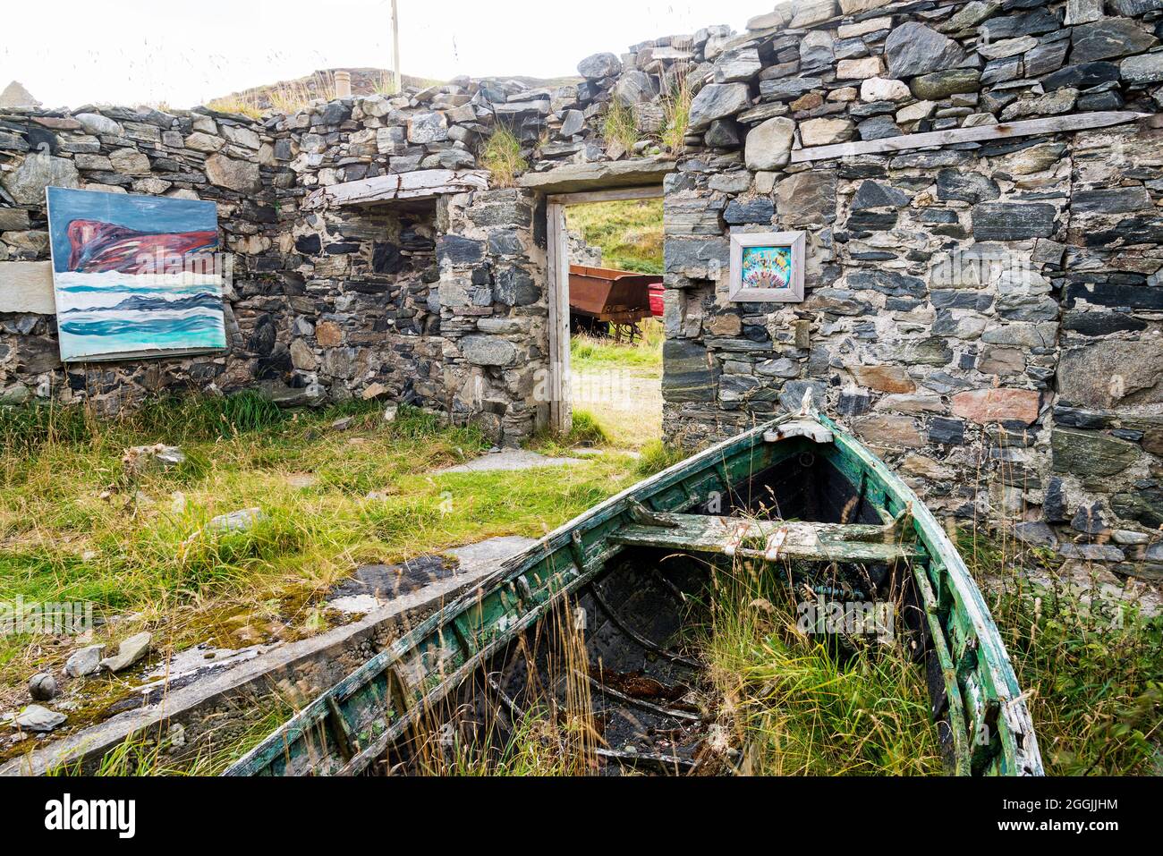Ein altes, ruiniertes und dachloses Gebäude mit alten Booten bildet eine ungewöhnliche Kunstgalerie in der Skerray Bay an der Nordküste Schottlands direkt vor der NC500. Stockfoto