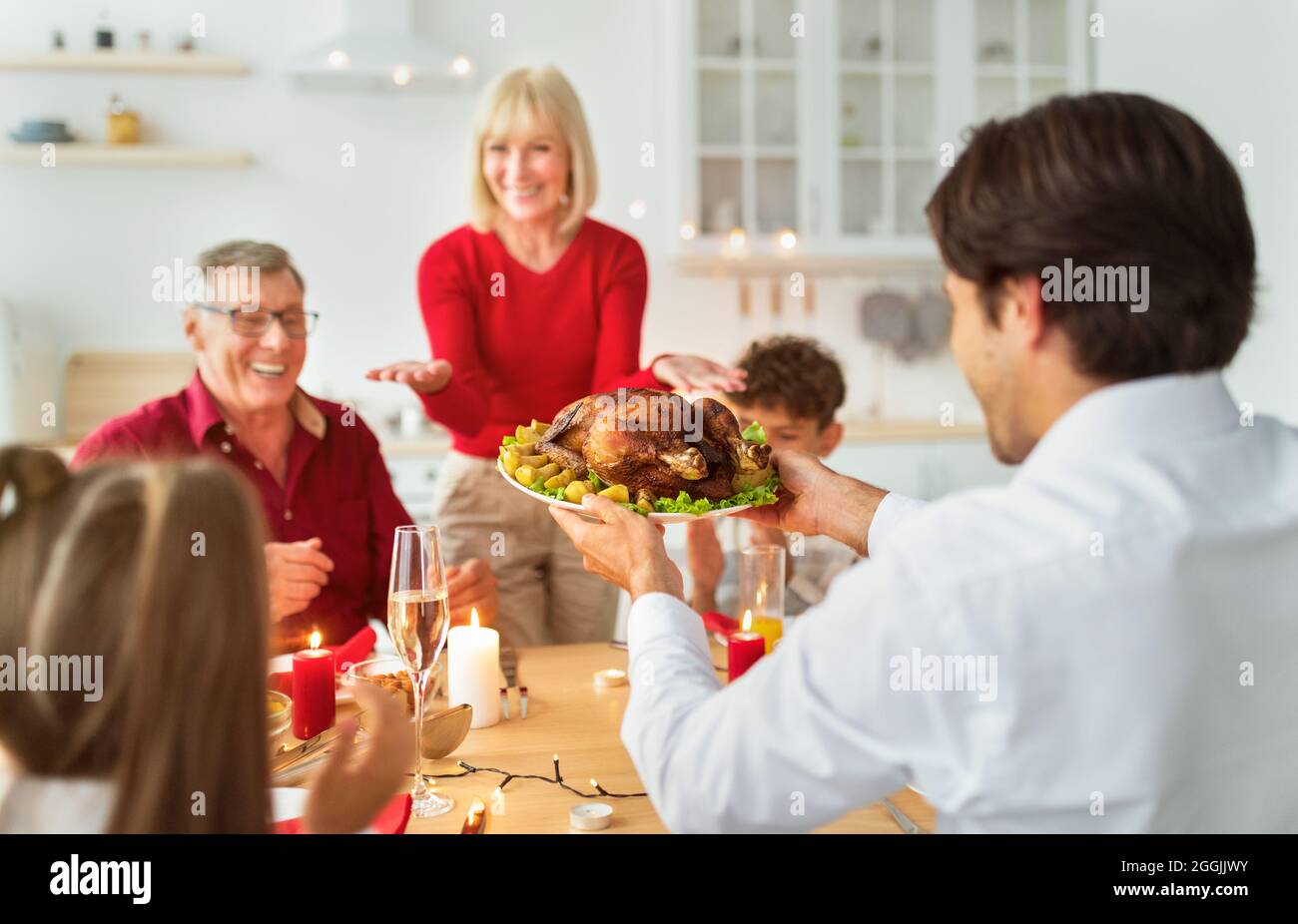 Junger Mann, der traditionelle Ferien in der türkei für große Großfamilie serviert und Thanksgiving oder Weihnachten zu Hause feiert Stockfoto