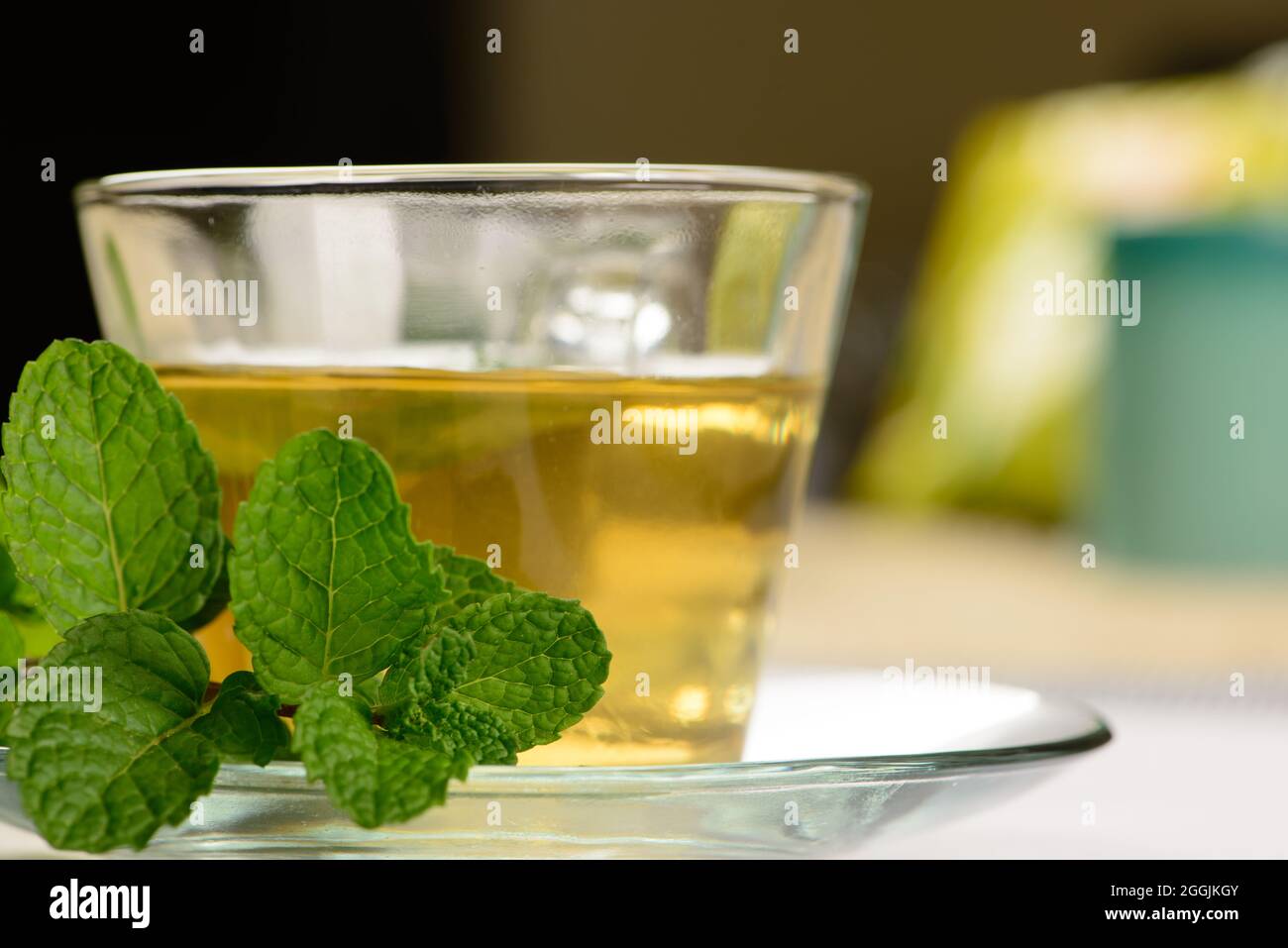 Minztee in transparenter Tasse mit Minzzweig daneben Stockfoto