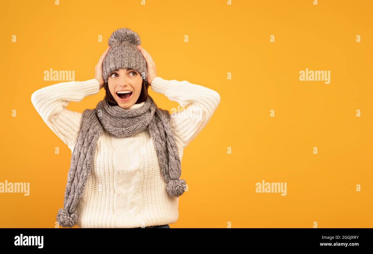 Es ist unglaublich. Überrascht junge Dame in warmen Pullover und gestrickten Set schockiert zu sehen, Umsatz, gelber Hintergrund Stockfoto