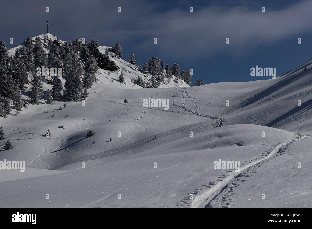 Spuren von Tourenski im Neuschnee mit Gipfelkreuz Stockfoto