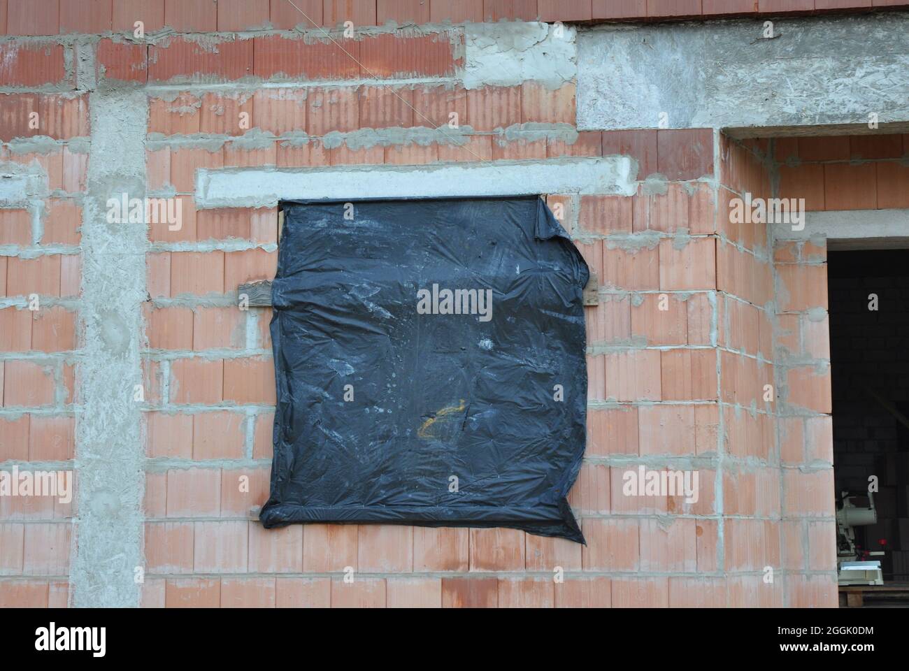 Schützen Sie unfertige Hausfenster für den Winter, um Schnee und Regen im Inneren zu vermeiden. Reduzierung der Kondensation in unfertigen Gebäuden im Winter Stockfoto