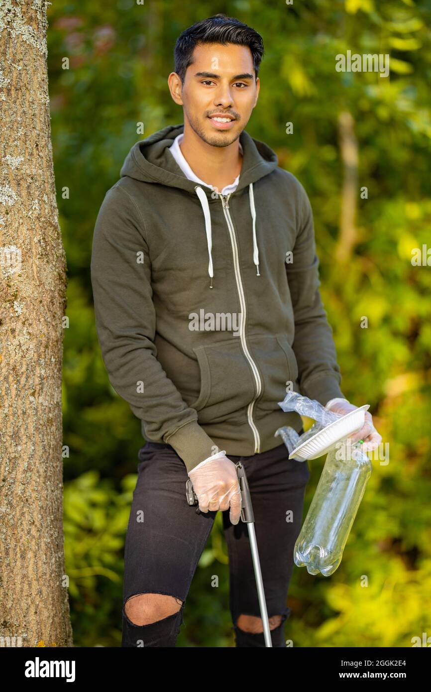 Stolzer Umweltschutz-Freiwilliger hält Müll und mechanischen Greifer Stockfoto