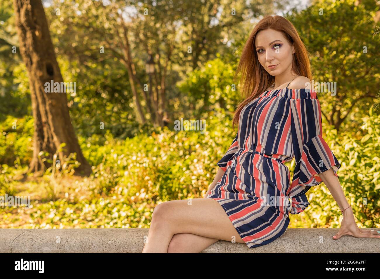Schöne kaukasische Frau, die auf Stein im Naturpark sitzt Stockfoto