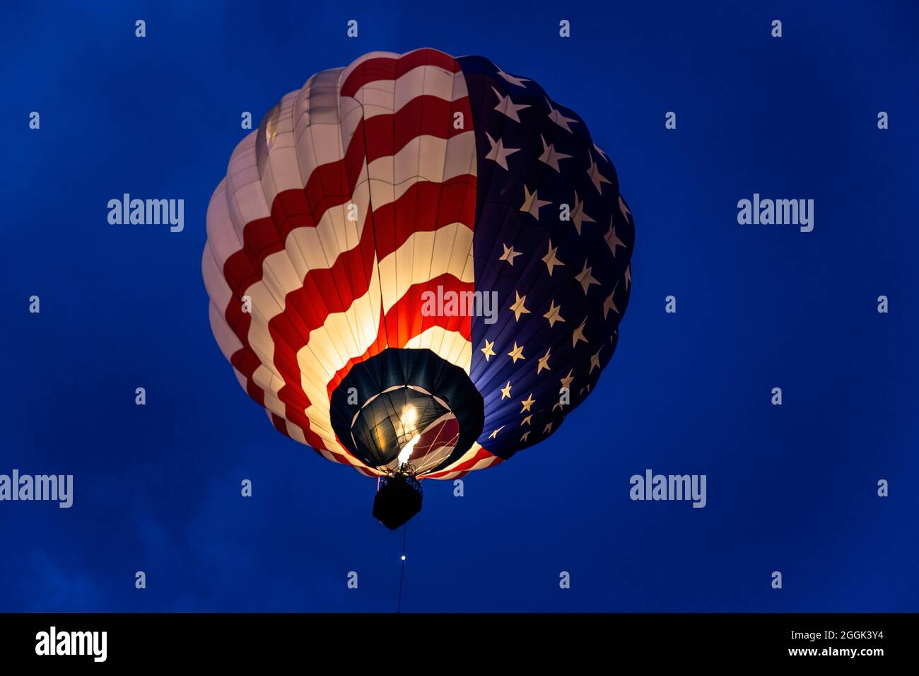 Beleuchtete Sterne und Streifen Heißluftballon fliegen während Dawn Patrol, Albuquerque International Balloon Fiesta, Albuquerque, New Mexico USA Stockfoto