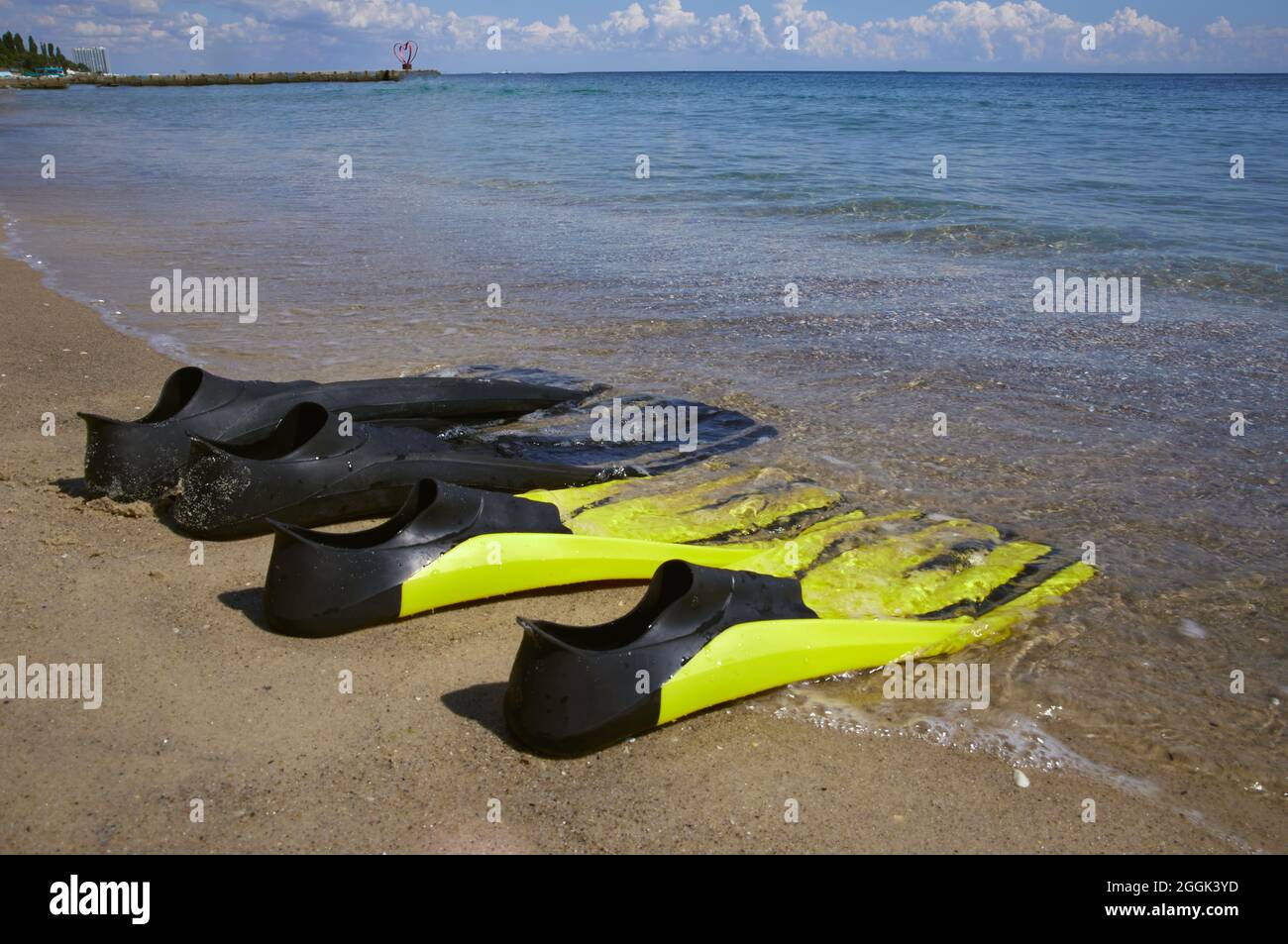 Zwei Paar Flossen liegen an der Küste in der Brandung. Sonniger Tag, Odessa Ukraine. Stockfoto